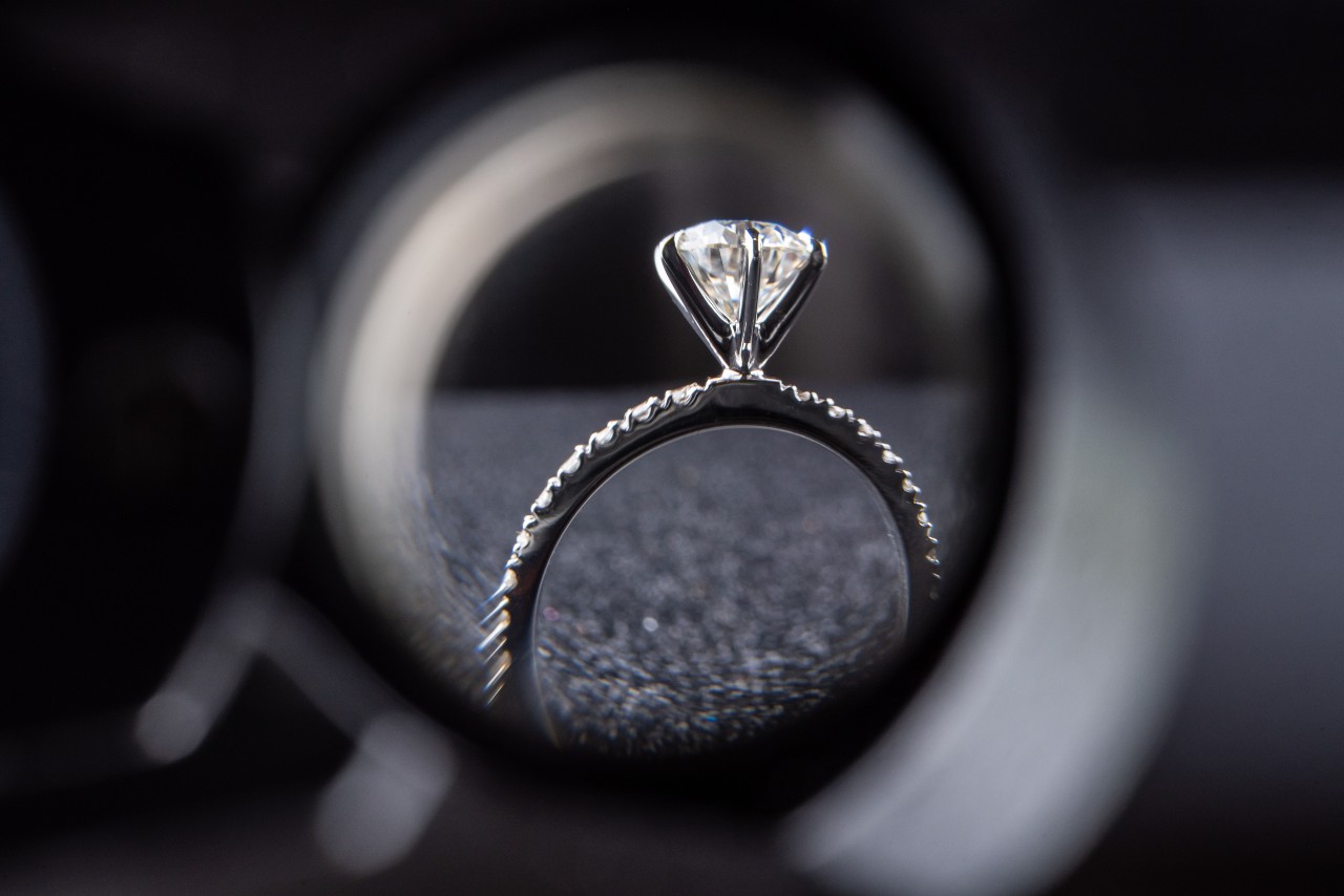 A view through a jeweler’s magnifying glass of a ring’s side profile.
