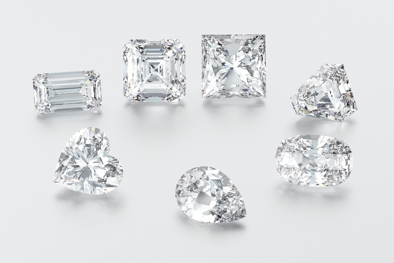 Seven diamonds of different cuts on a white surface