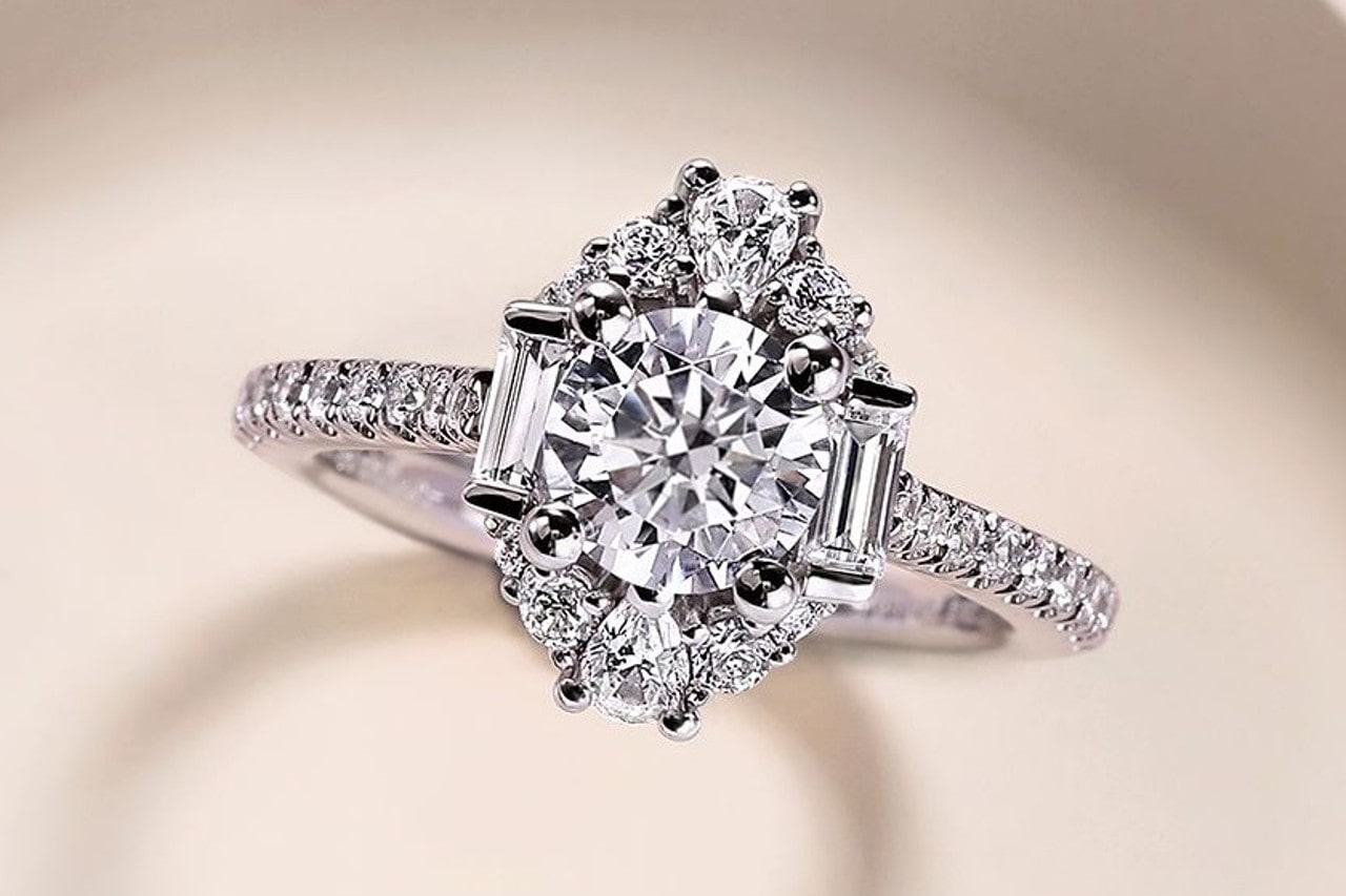 a white gold engagement ring featuring an elaborate halo, side stones, and round cut center stone