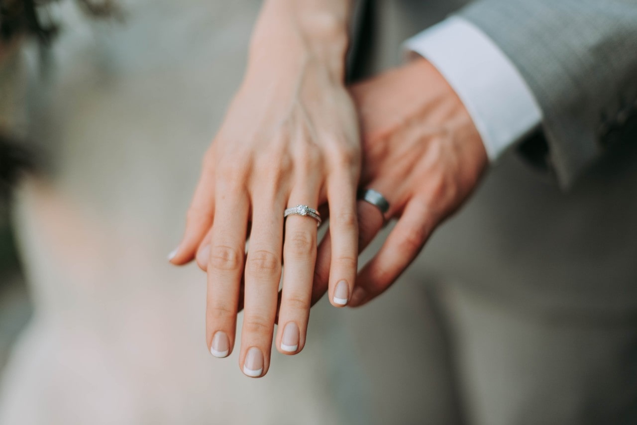 a man and woman’s hand wearing platinum wedding bands