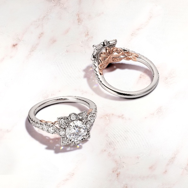 The front and back view of an intricate blooming halo engagement ring with rose gold details along the white gold band that has larger to smaller side stone diamonds