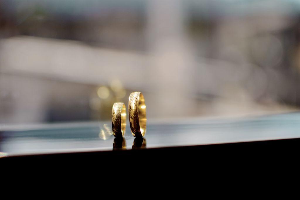 A matching pair of gold wedding bands sits on a window seal overlooking the cityscape
