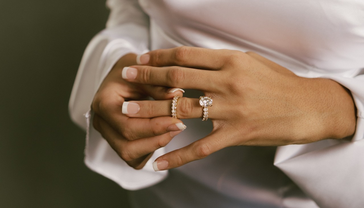 A diamond eternity band being put on a woman’s hand