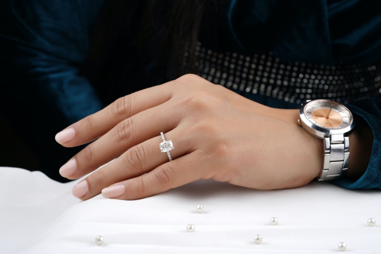 Woman’s hand wearing a silver radiant cut diamond ring with sidestone accents