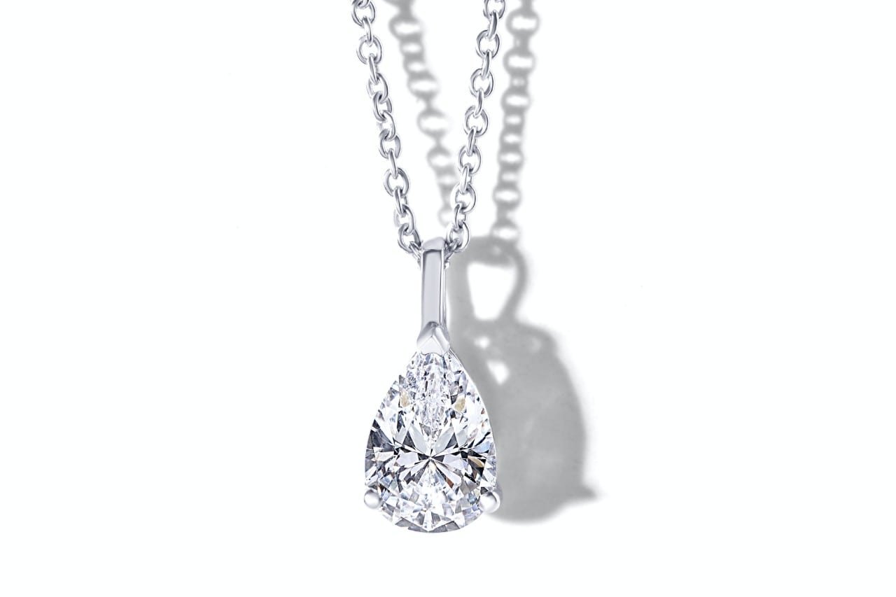 a white gold pendant necklace featuring a marquise cut diamond