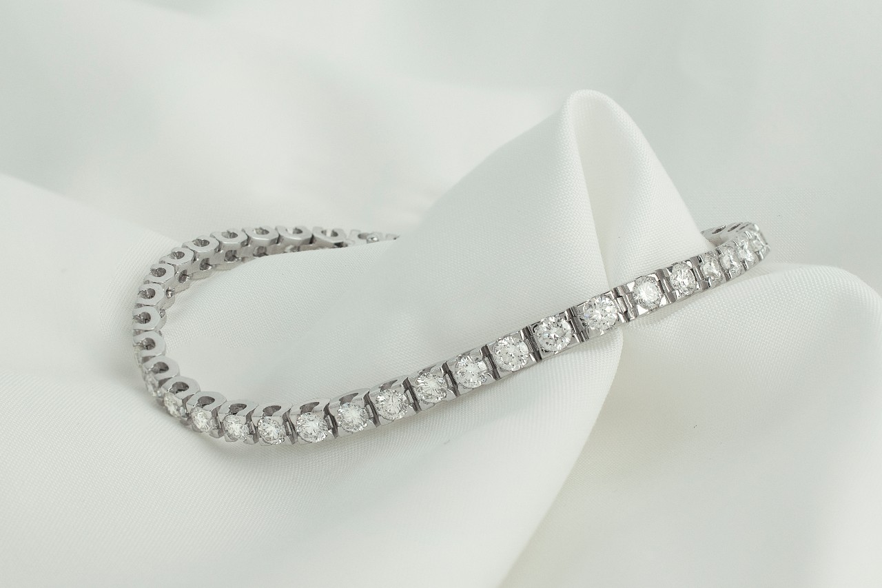 a white gold tennis bracelet lying on a piece of white cloth