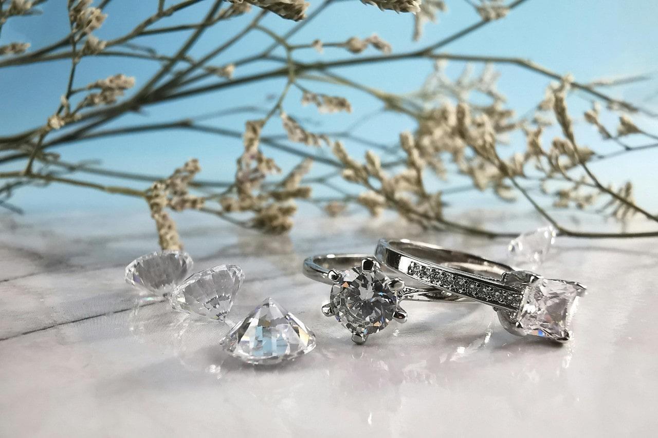 An elegant display of gorgeous diamond bridal jewelry next to round cut diamonds on a refreshing background.