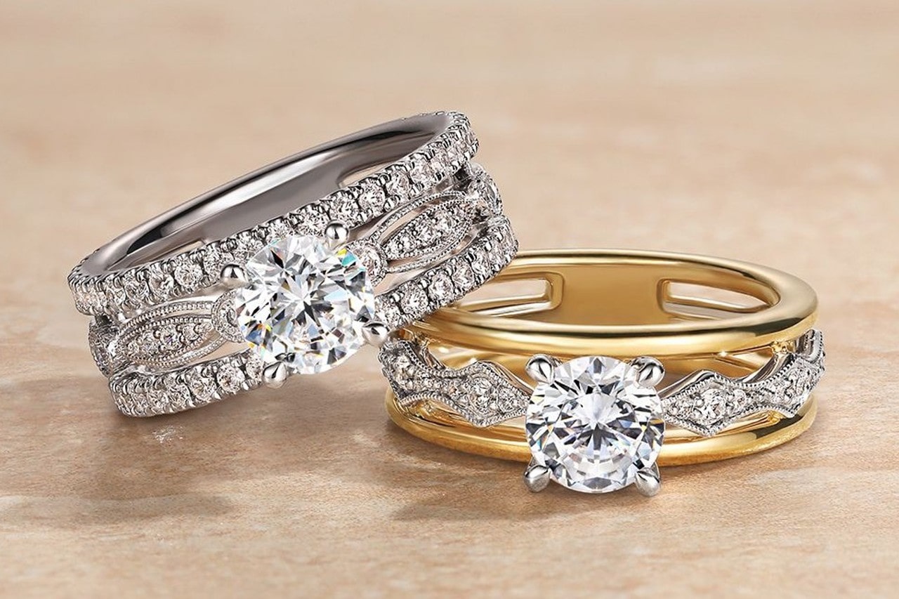 two elaborately designed engagement rings, one featuring only white gold, the other featuring both white and yellow gold