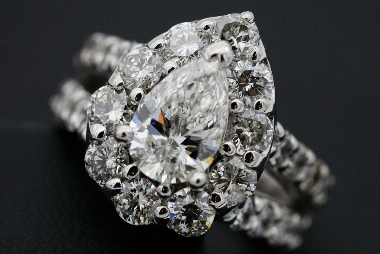 A close-up of a stunning pear shape halo engagement ring with a split side stone band.