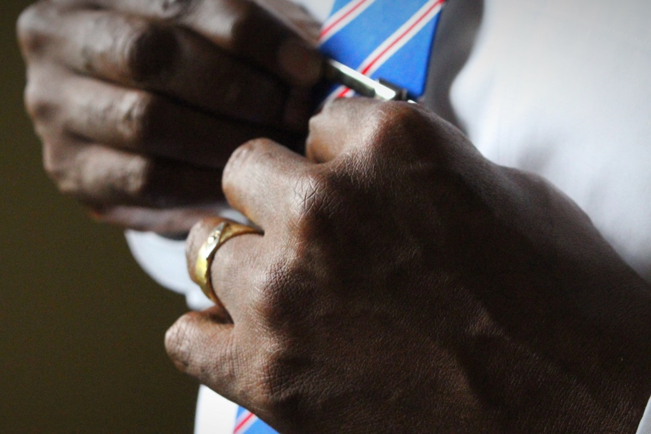 a man adjusting his tie and wearing a mixed metal wedding band