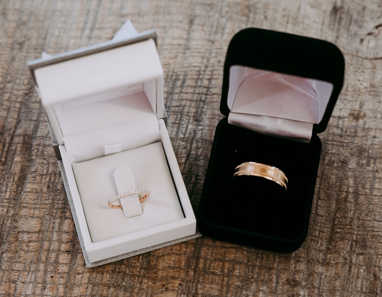 A white and black jewelry box with yellow gold wedding bands inside.