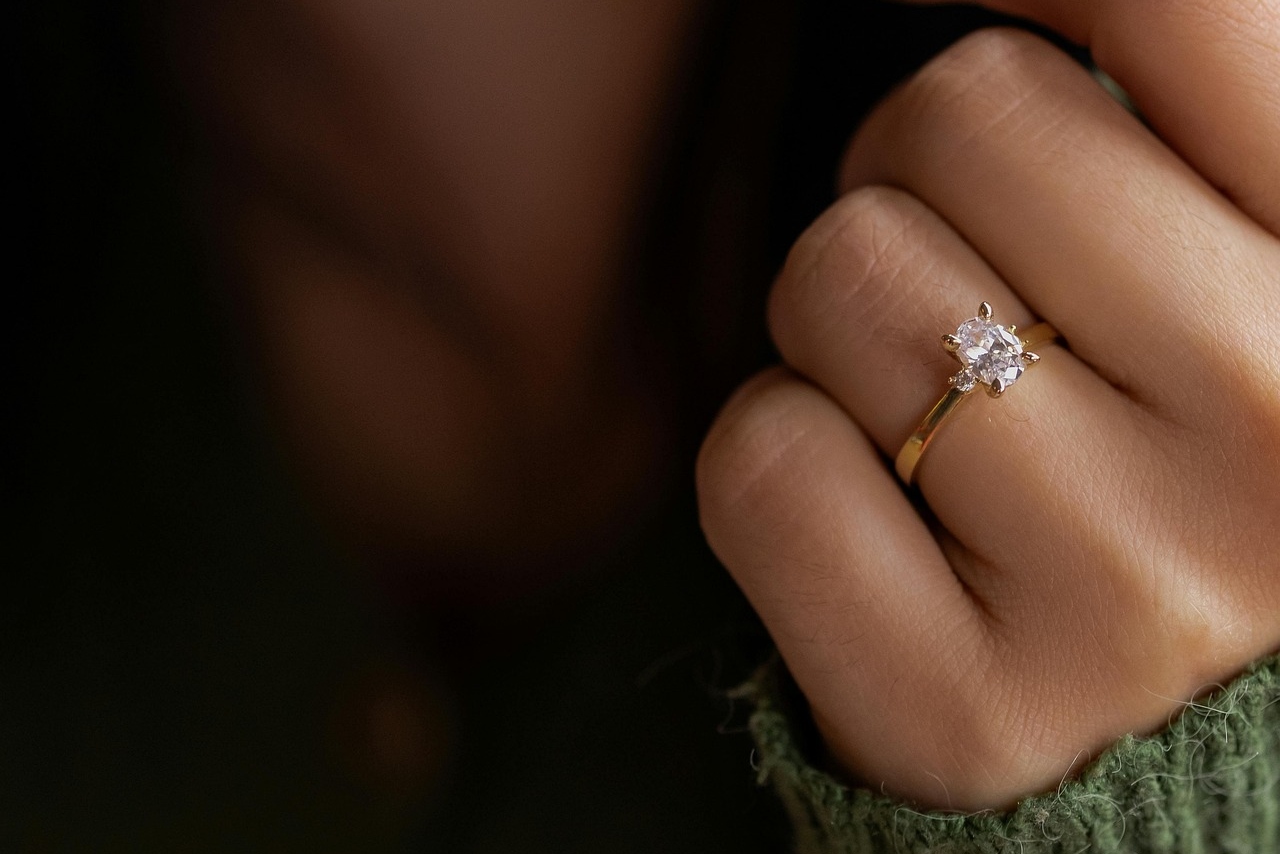 A yellow gold diamond solitaire engagement ring on a woman&rsquo;s finger