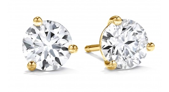 a pair of diamond stud earrings in a three prong, gold setting