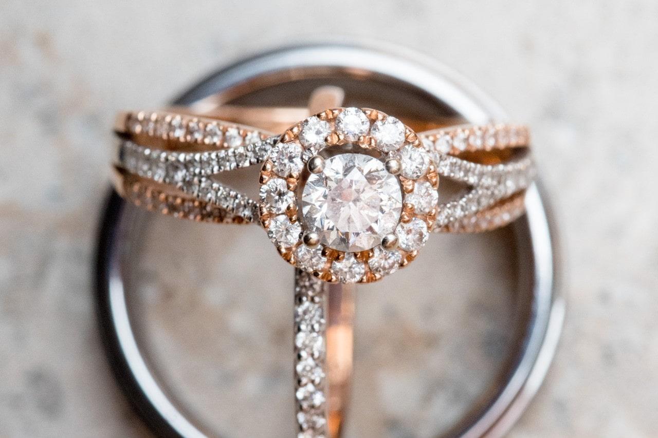 A mixed metal engagement ring sits with two wedding bands on a marble surface.