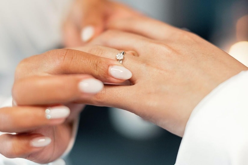 A bridesmaid helping a bride with her engagement ring on the day of her wedding