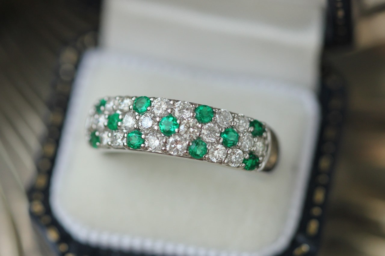 a diamond and emerald pave set wedding band in a ring box